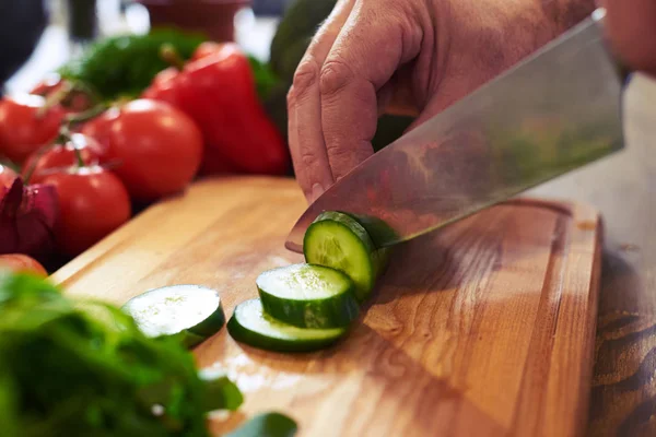 Hands of chef slicing cucumber with a knife on chopping board — Stock Photo, Image