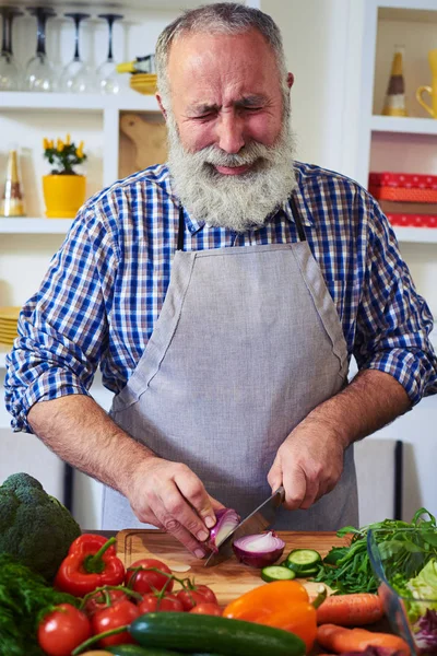 Handsome man cutting onion on chopping board — Stock Photo, Image