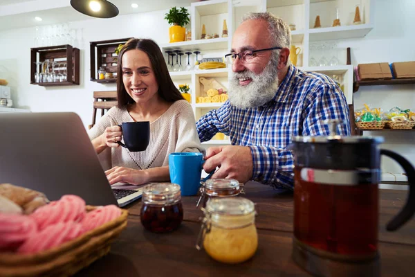 Bajo ángulo de sonriente pareja sentada frente a netbook y mirar —  Fotos de Stock