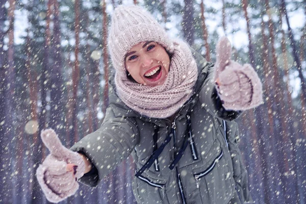 Fröhliches junges Model im Winterwald mit erhobenem Daumen — Stockfoto