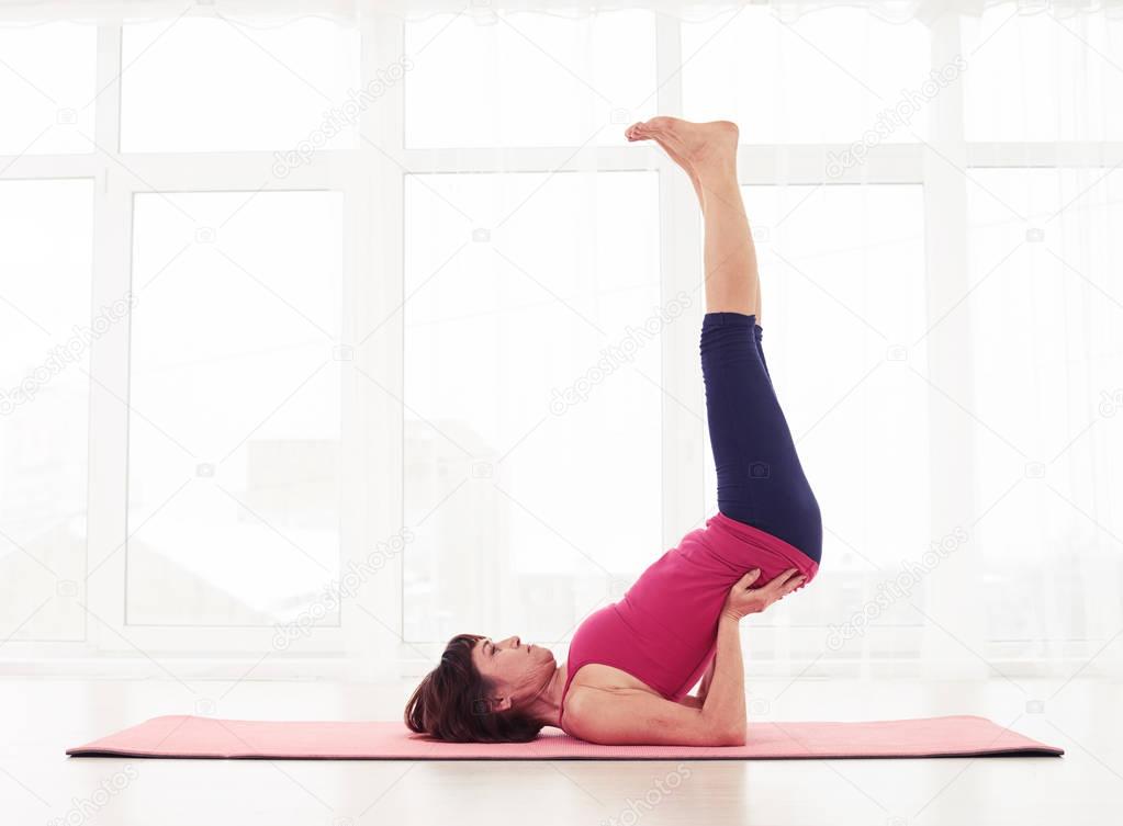 Caucasian female having a workout on a yoga mat in the gym
