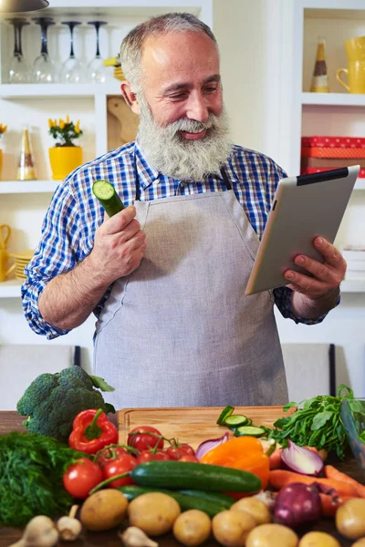 Homem moderno à procura de uma receita com a ajuda de tablet de pé — Fotografia de Stock