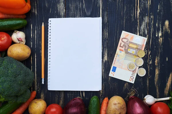 Laptop voor aankoop met geld omringd met rauwe biologische groenten — Stockfoto