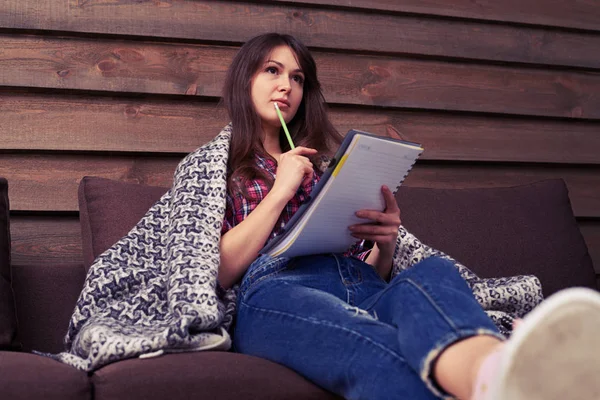 Chica pensativa haciendo nota en el libro de texto — Foto de Stock