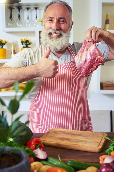 Portrait of a cheerful male cook holding fresh meat and holding — Stock Photo, Image