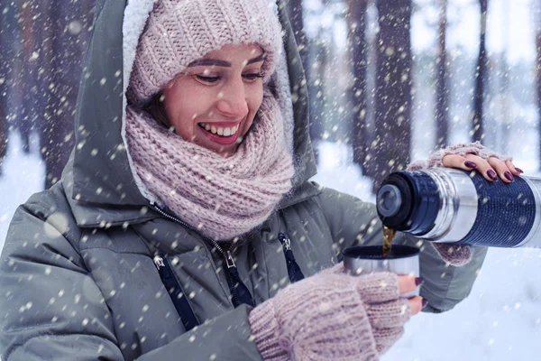 Seitenansicht einer Frau, die sich mit heißem Tee aus der Thermoskanne aufwärmt — Stockfoto