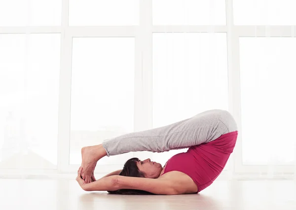 Slanke yogini liggend op de rug op de mat in een yoga positie benen — Stockfoto