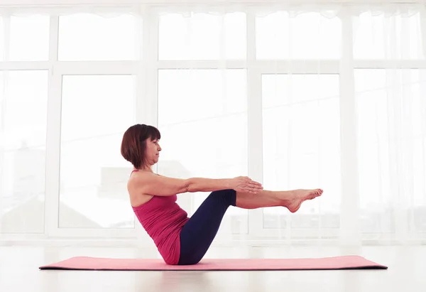 Sportliche Frau beim seitlichen Bauchmuskeltraining in einem Fitnessstudio auf einer Yogamatte — Stockfoto