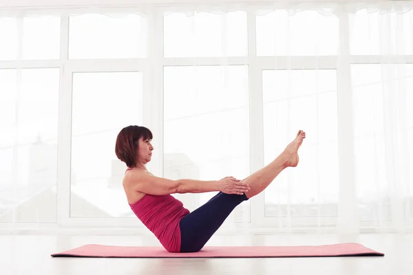 Deportiva madura hembra haciendo abdominales con las piernas levantadas en el — Foto de Stock