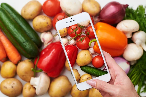 Bovenaanzicht van telefoon maakt foto van verse groenten — Stockfoto