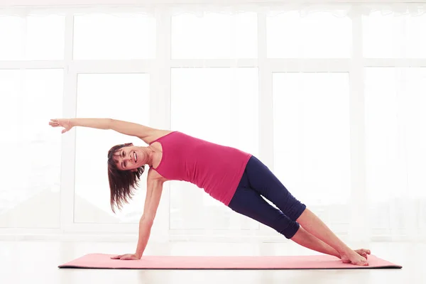 Kvinna utförs en räckte sida planka pose i gymmet — Stockfoto