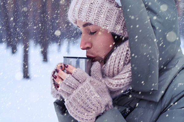 Kobieta dostaje ciepły pijąc herbatę w lesie zimą — Zdjęcie stockowe