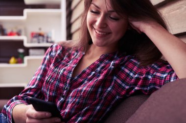 Mutlu bir şekilde kanepede otururken kameraya gülümseyen kadın