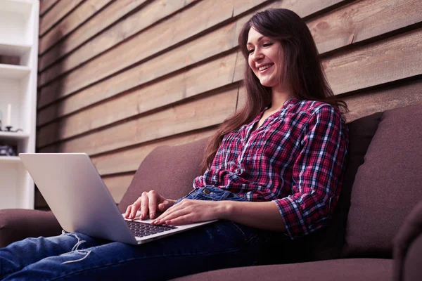 Mulher atraente está relaxando no sofá confortável e usando colo — Fotografia de Stock