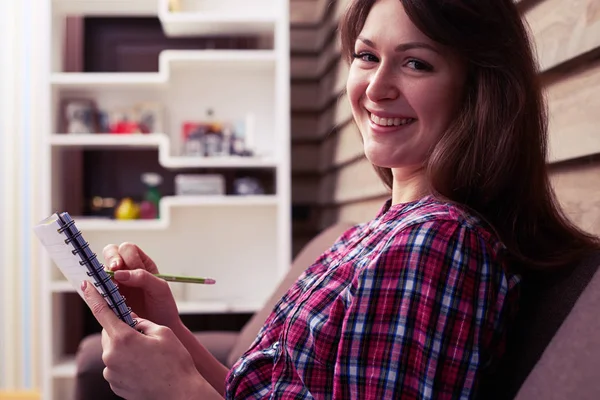 Delightful smiley girl looking at the camera while holding a not — Stock Photo, Image