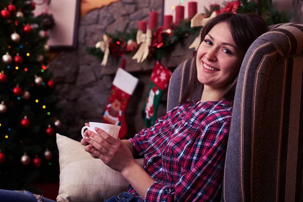 Overjoyed youth relaxing in an armchair against decorated firepl — Stock Photo, Image