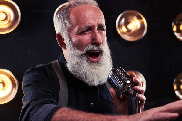 Старший певец с ретро-микрофоном указывая рукой в ди — стоковое фото