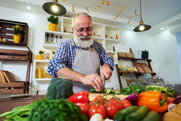 Uomo barbuto sorridente di buon umore preparare il cibo per la cena — Foto Stock