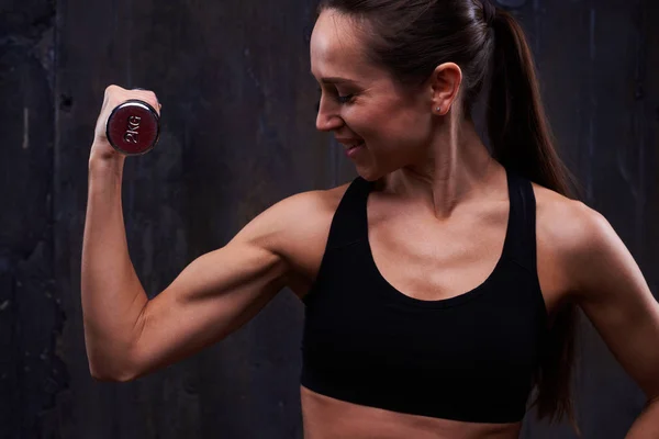 Mujer decidida durante el entrenamiento perseverante en el estudio oscuro —  Fotos de Stock