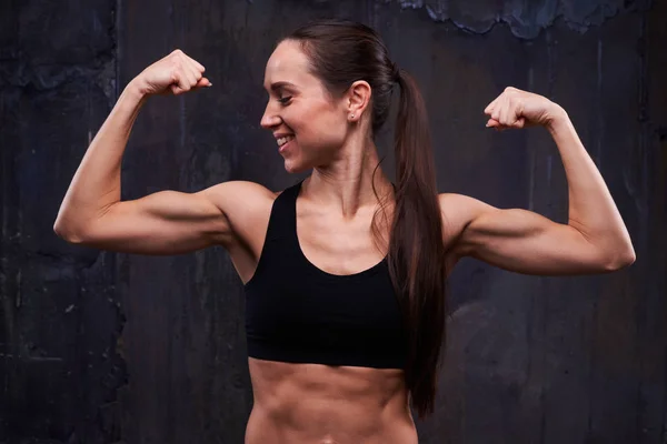 Energetic sportswoman flexing hands isolated over black backgrou — Stock Photo, Image