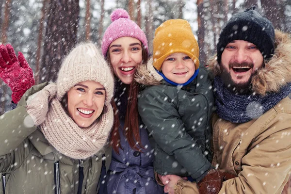 Happy family of four standing in the snowy forest in winter
