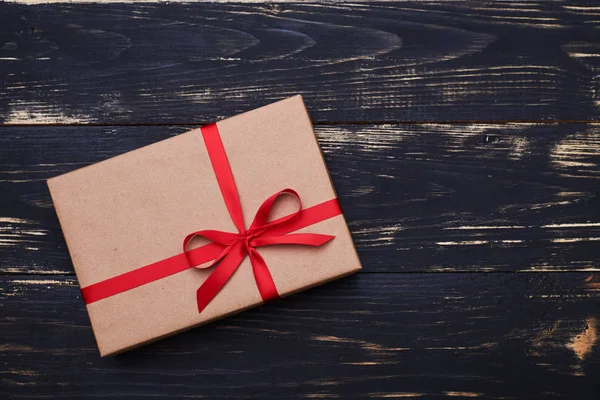 Κλασσικό δώρο κουτί τυλιγμένο σε ένα καφέ εκλεκτής ποιότητας χαρτί δεμένο με κόκκινο — Φωτογραφία Αρχείου