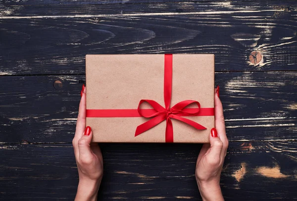 Eller bir kahverengi hediye vintage paketi kırmızı kurdele ile tutun — Stok fotoğraf