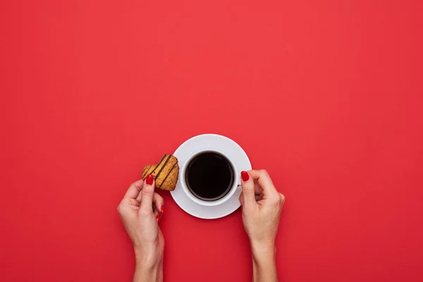 Mujer manos sosteniendo la taza de café con galletas pequeñas en una forma de h — Foto de Stock