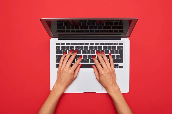 Mulher digitando em um teclado de laptop em vermelho plano leigos fundo — Fotografia de Stock