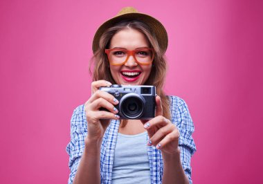 Kız turuncu gözlük gümüş bir retro kamera ile fotoğraf çekme 