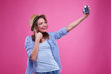 Gülümseyen trendy kız selfie pembe bir arka plan karşı alıyor 