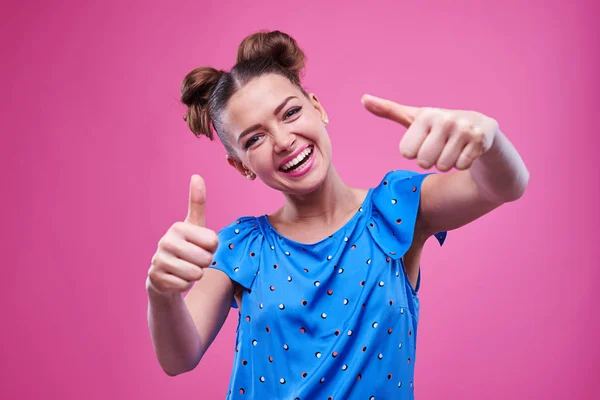 Энтузиастичная молодая девушка, показывающая два больших пальца вверх со смешным выражением лица — стоковое фото