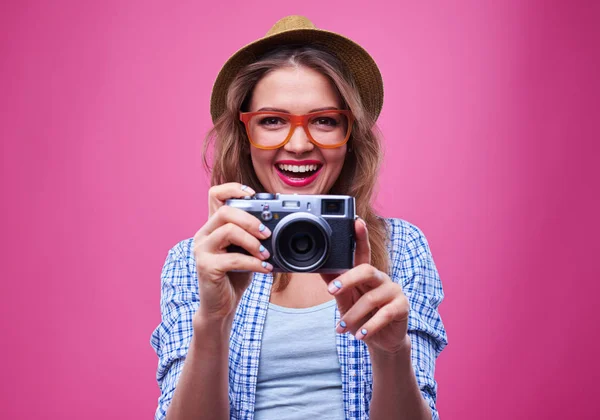 Menina em óculos laranja tirar foto com uma câmera retro prata — Fotografia de Stock