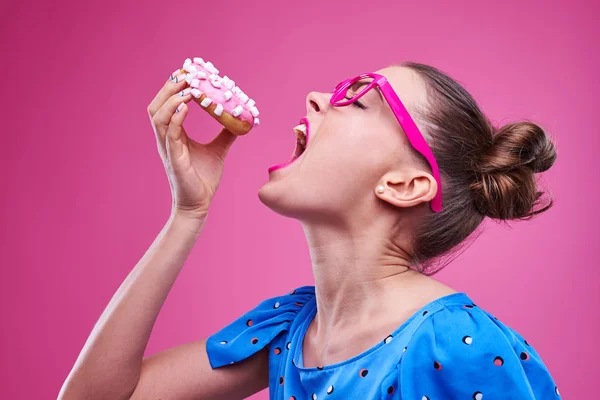 Girl is gladly going to bite a sprinkled donut with marshmallow — Stock Photo, Image