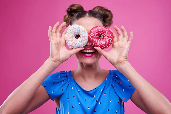 Szczęśliwa młoda dziewczyna zerkające przez dwa posypane donutnuts — Zdjęcie stockowe