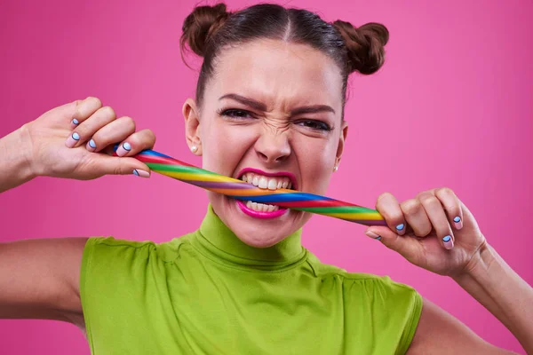 Portrait shot of angry girl biting long lollipop — Stock Photo, Image