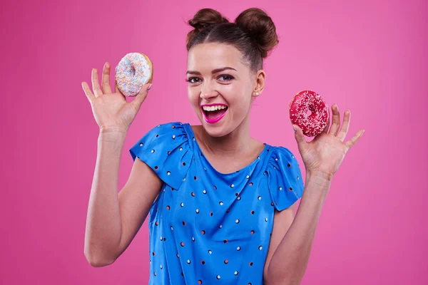 Chica joven positiva sosteniendo dos rosquillas espolvoreadas —  Fotos de Stock