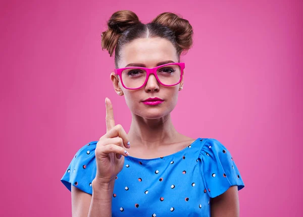 Schlanke, gut aussehende Frau in pinkfarbener Brille mit erhobenem Zeigefinger — Stockfoto