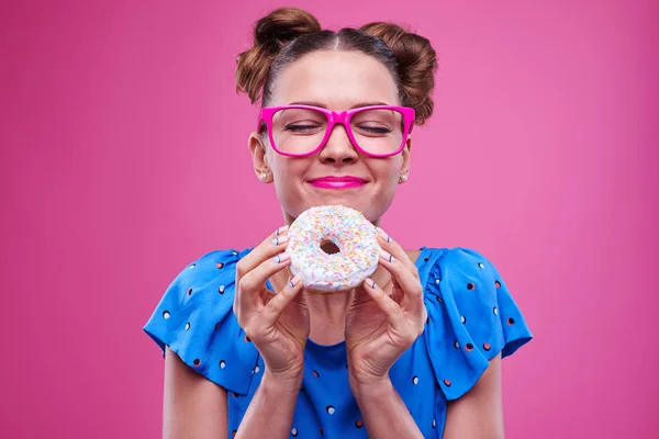 Leende kaukasiska flicka med slutna ögon håller en donut — Stockfoto