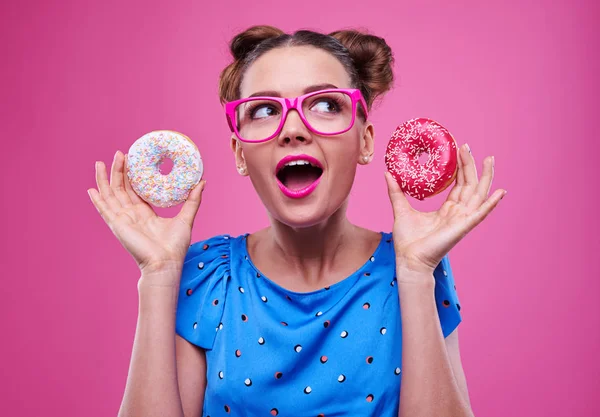 Surprised lady in pink glasses looking upwards while holding two — Stock Photo, Image