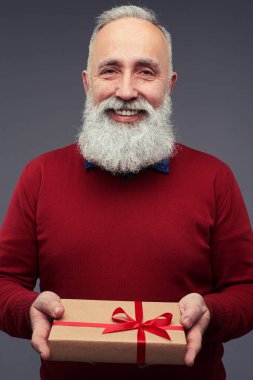 Kırmızı kazaklı bir hediye kutusu tutarak sakallı adam 