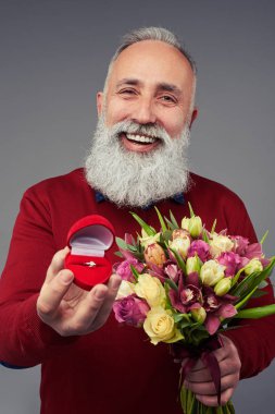 Genel olarak gülümseyen olgun adam hediye kutusu alyans ile tutarak bir