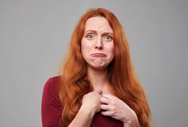 Разочарованная молодая женщина с рыжими волосами в студии — стоковое фото