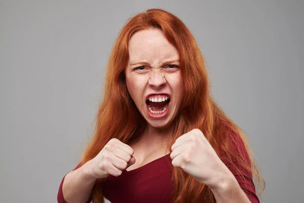 Mujer ansiosa con el pelo rojo sosteniendo dos puños — Foto de Stock