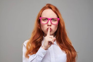 Kızıl saçlı genç sessizlik işaret parmağını dudaklarına yakınındaki tarafından gösterilen 