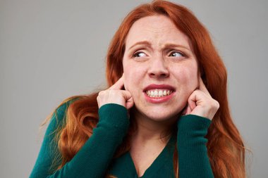 Kızıl saçlı kadın parmaklarını kulakları tıkalı çok korkuyor