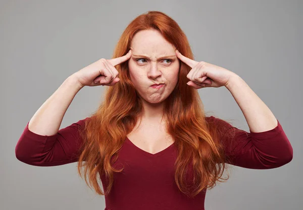 Puzzled young woman with auburn hair pressing her forehead with — Stock Photo, Image