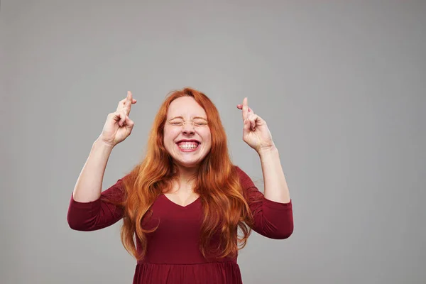 Ung kvinna med rödbrunt hår att hålla hennes tummarna — Stockfoto