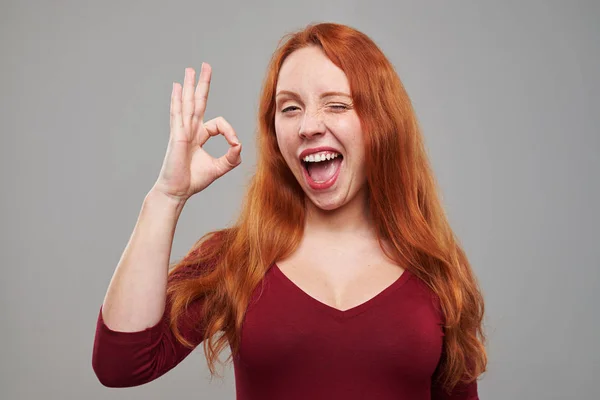 Erheiterte Frau macht Okay-Geste und zwinkert — Stockfoto