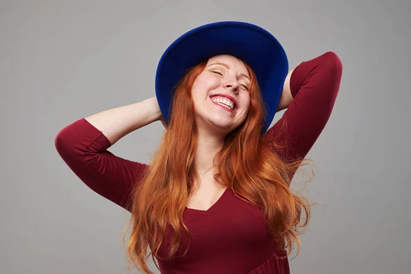 Uvolněná mladá žena v vínová klobouku pózuje s rukama za hlavou — Stock fotografie